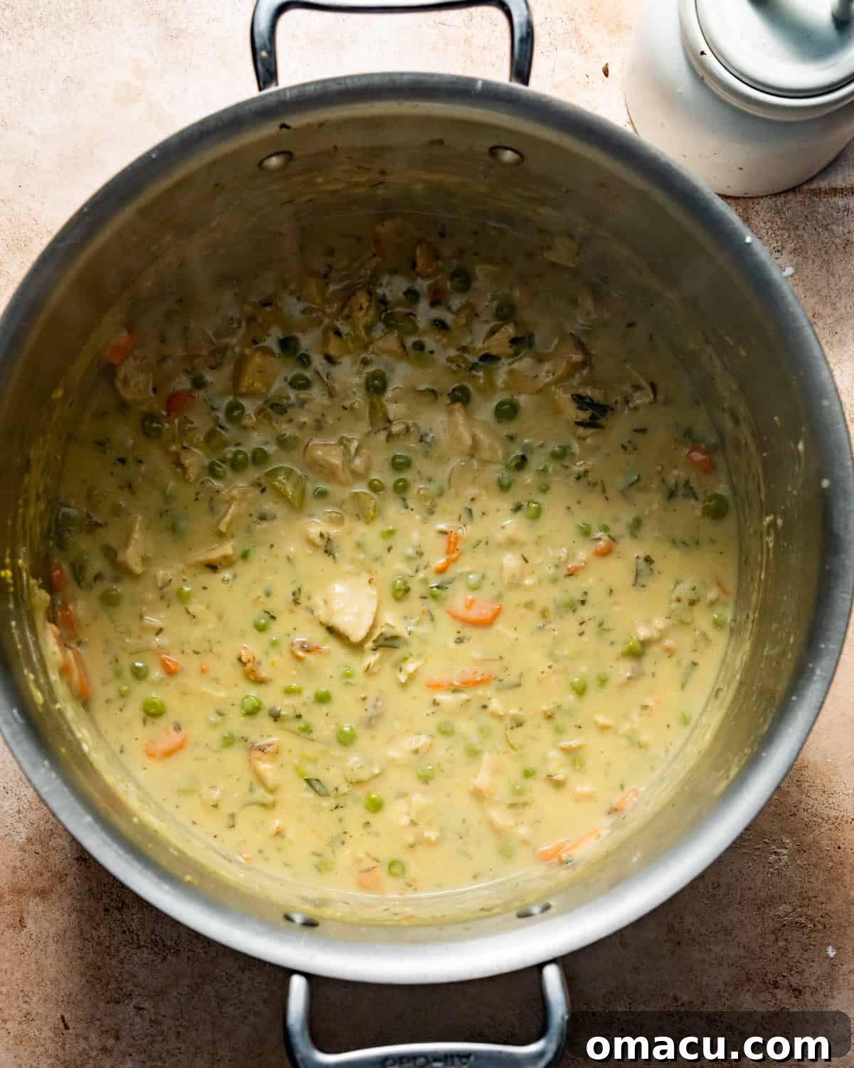 The rich and creamy chicken pot pie filling simmering in a large pot, ready for the chicken and cheese.