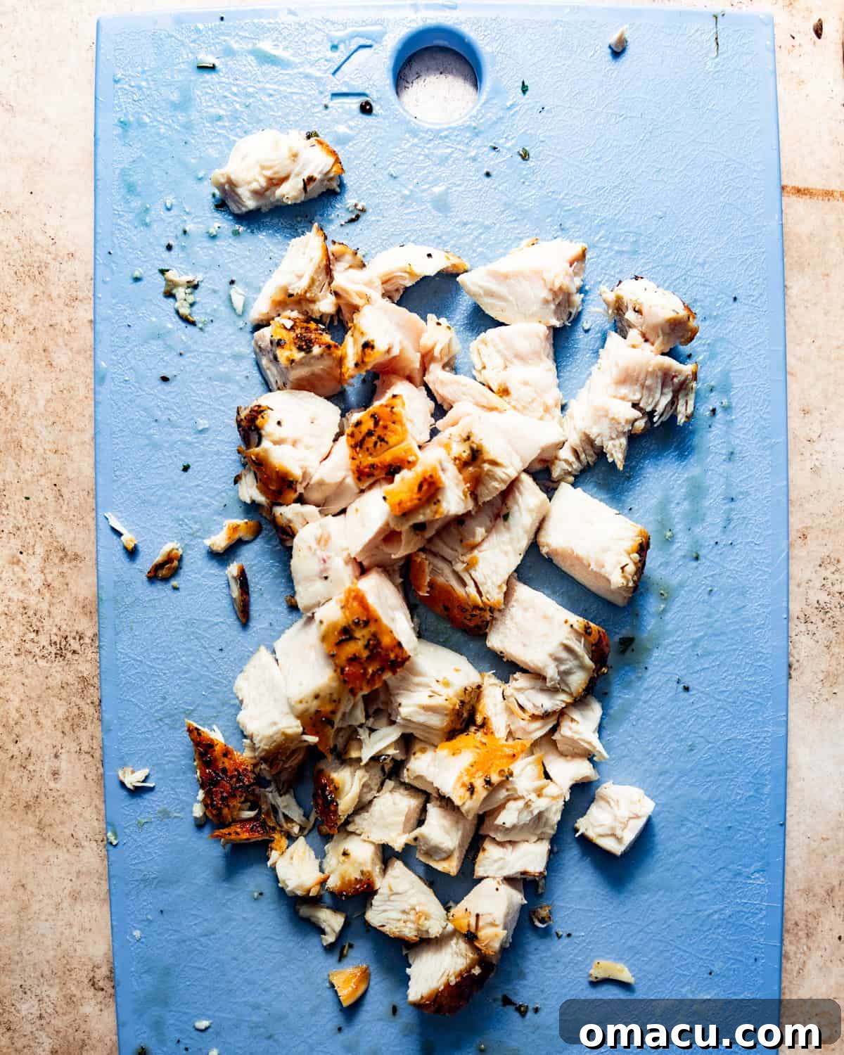 Cooked chicken breasts on a cutting board, freshly chopped into bite-sized pieces for the pot pie.