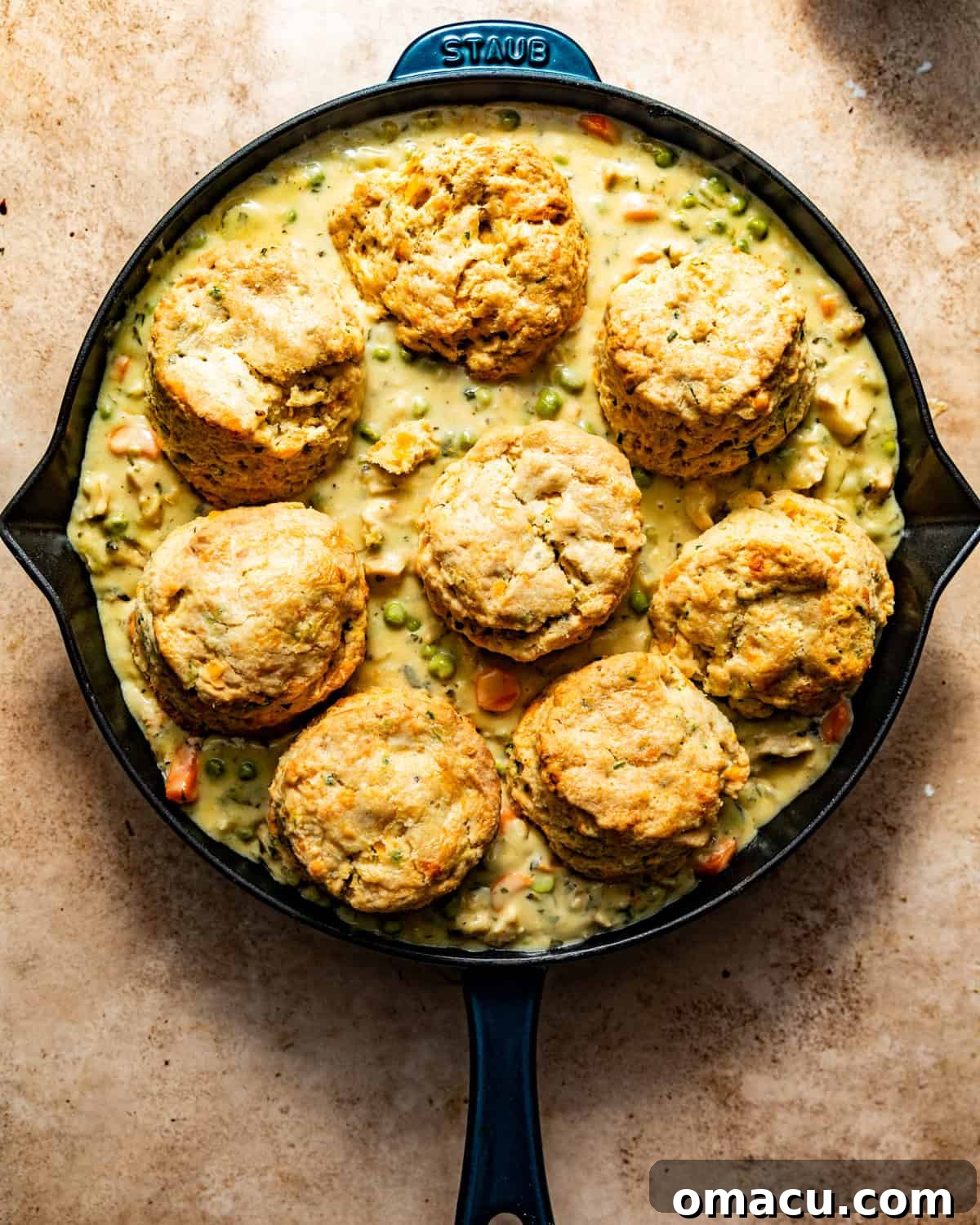 Chicken pot pie nestled in a cast iron skillet, topped with golden cheddar bay biscuits, ready for the oven.