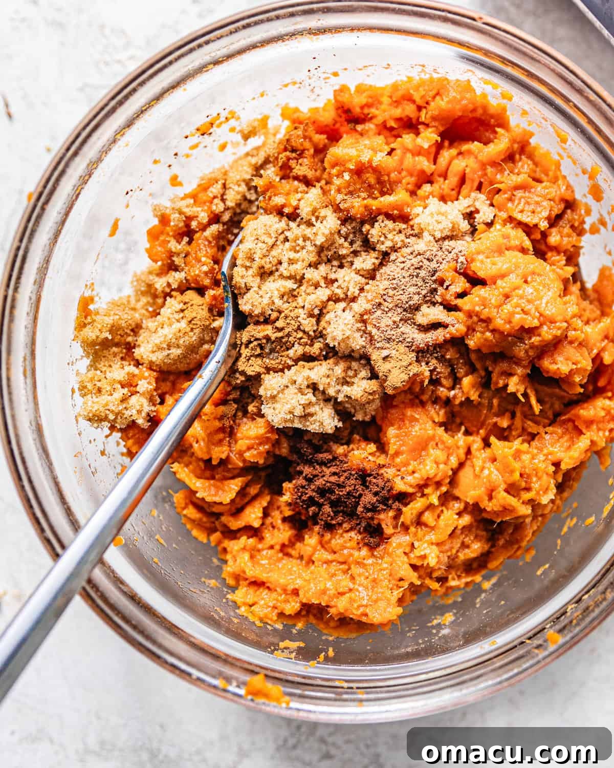 Mashed sweet potatoes in a bowl, infused with the warm spices of cinnamon, brown sugar, and nutmeg, creating a fragrant puree.