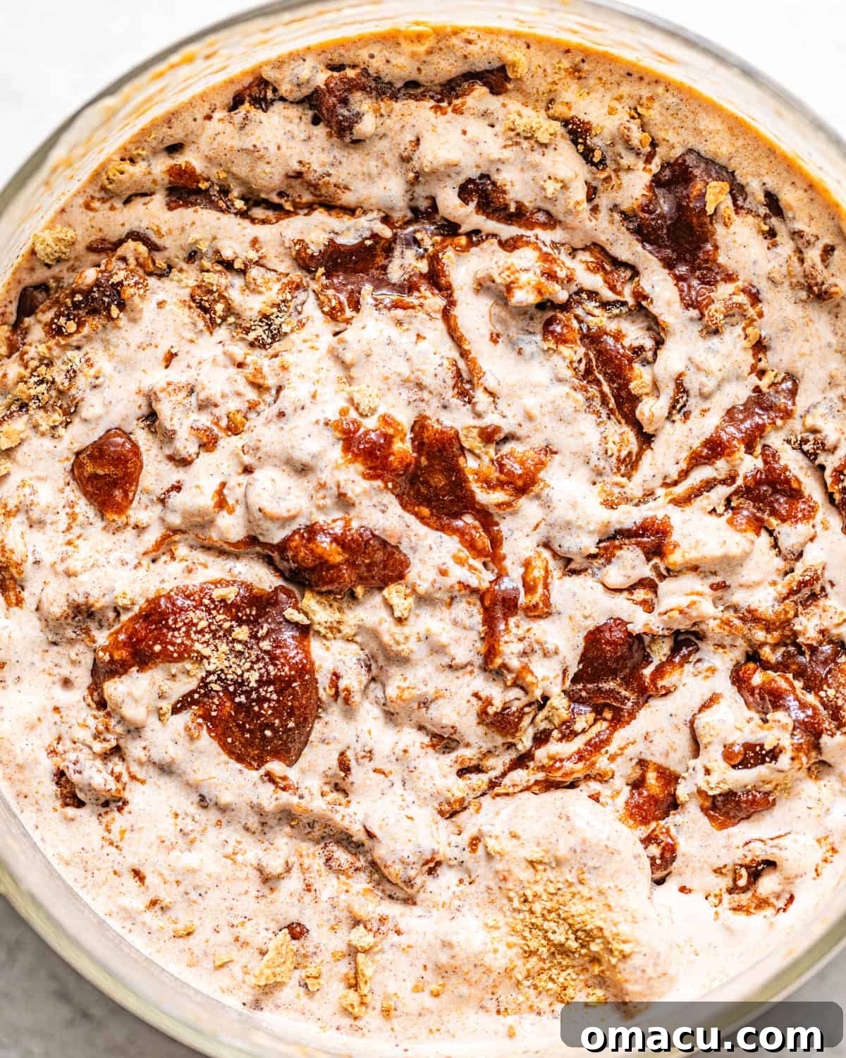 A scoop of sweet potato pie ice cream in a bowl, beautifully garnished with a distinct cinnamon swirl and crunchy graham cracker pieces on top.