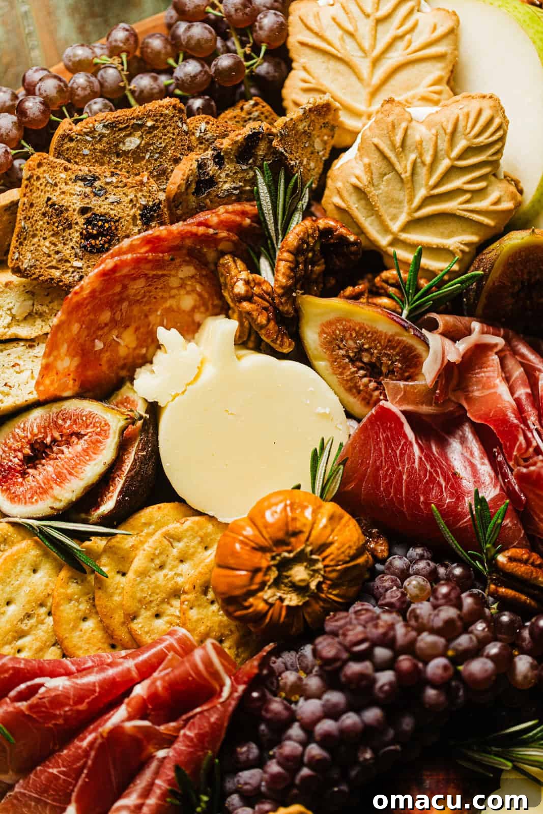 Close-up photograph of an assortment of cured meats and artisanal cheeses beautifully arranged on a rustic Fall Charcuterie Board.