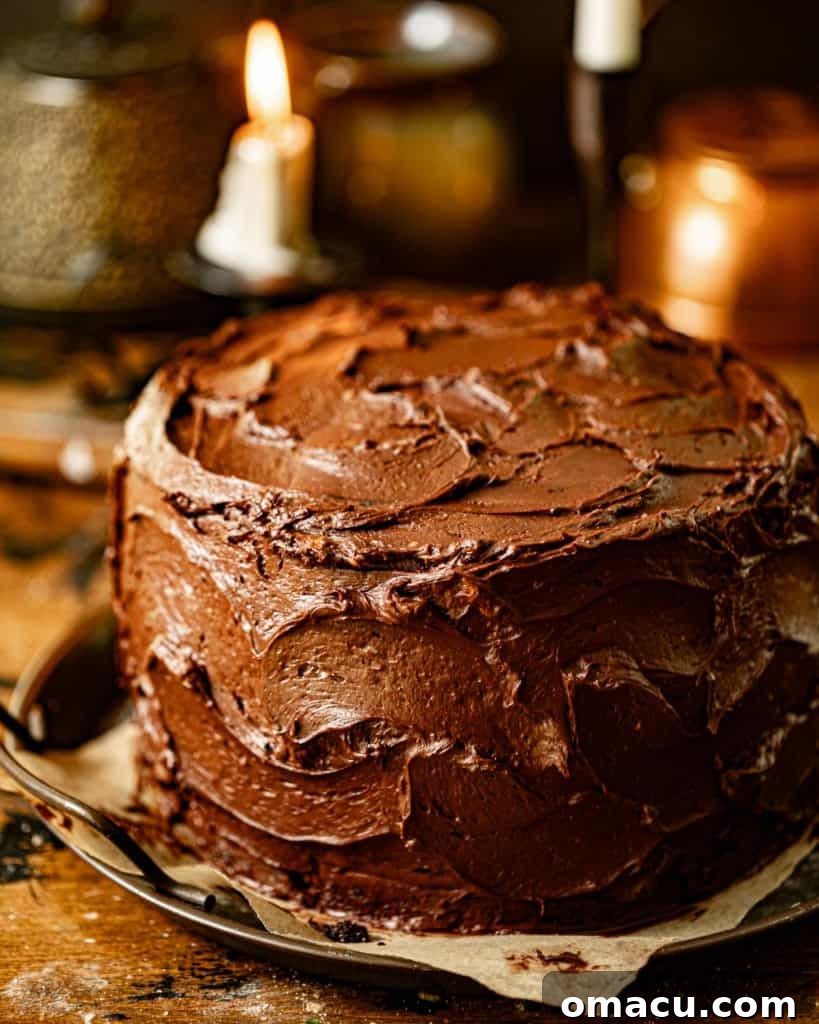 The magnificent Matilda's chocolate cake, fully frosted and decorated, sitting on a serving tray with lit candles and soft lighting.