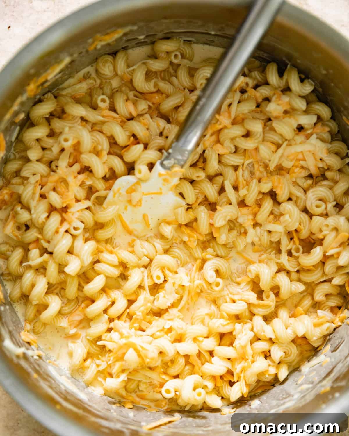 Cooked cavatappi macaroni pasta coated in a rich, creamy cheese sauce within a large pot.