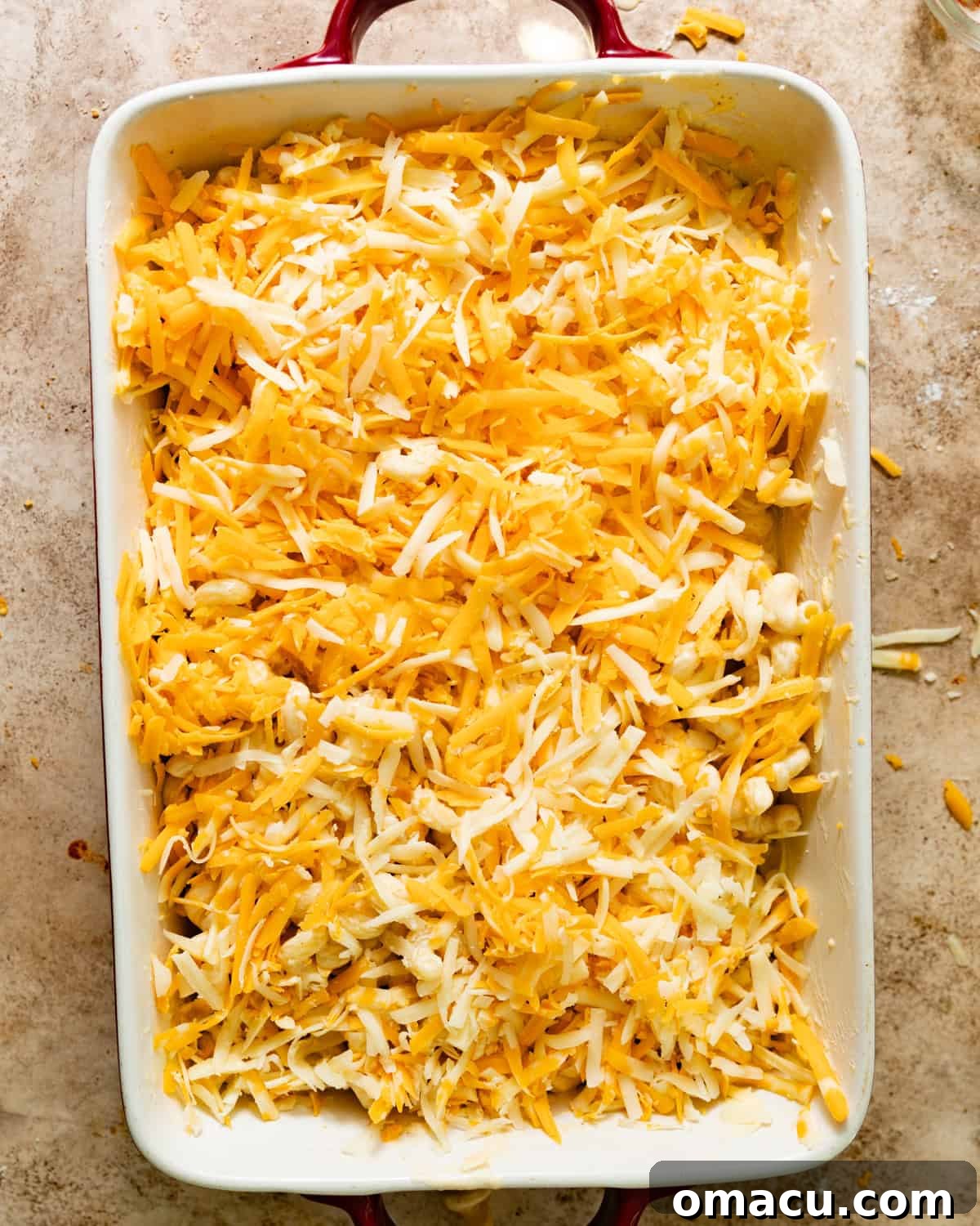 The assembled baked macaroni and cheese in a baking dish, ready for the oven, with layers visible and a generous cheese topping.