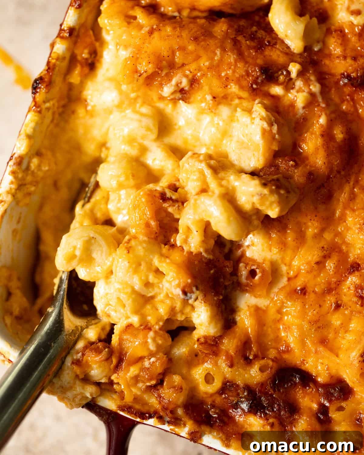 A tantalizing close-up photo of the finished baked macaroni and cheese in a baking dish, showcasing its bubbly, golden top.