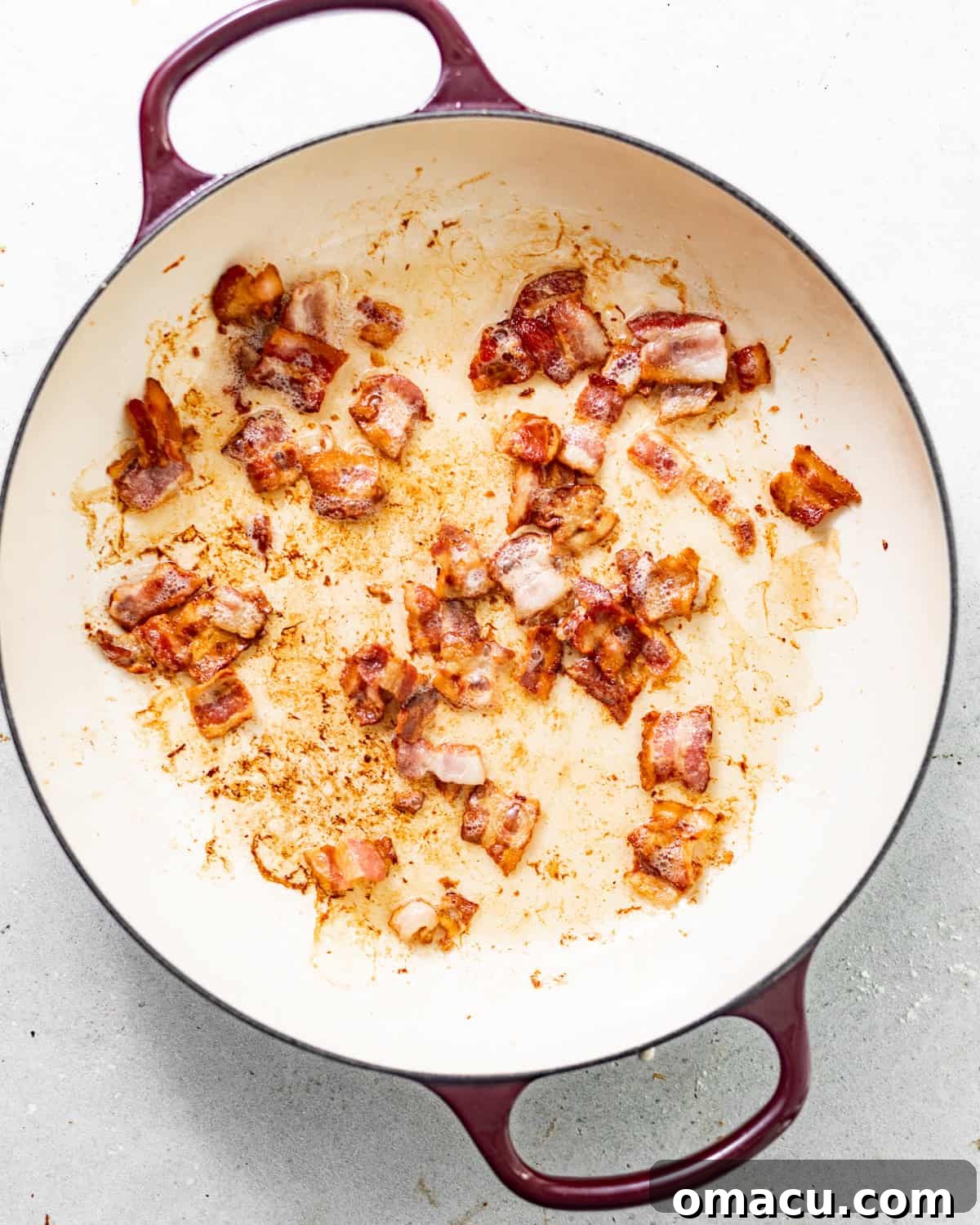 Crispy bacon sizzling in a large Dutch oven over medium heat on a stovetop.