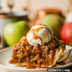 A slice of salted caramel Dutch apple pie on a plate with ice cream and salted caramel sauce on top.