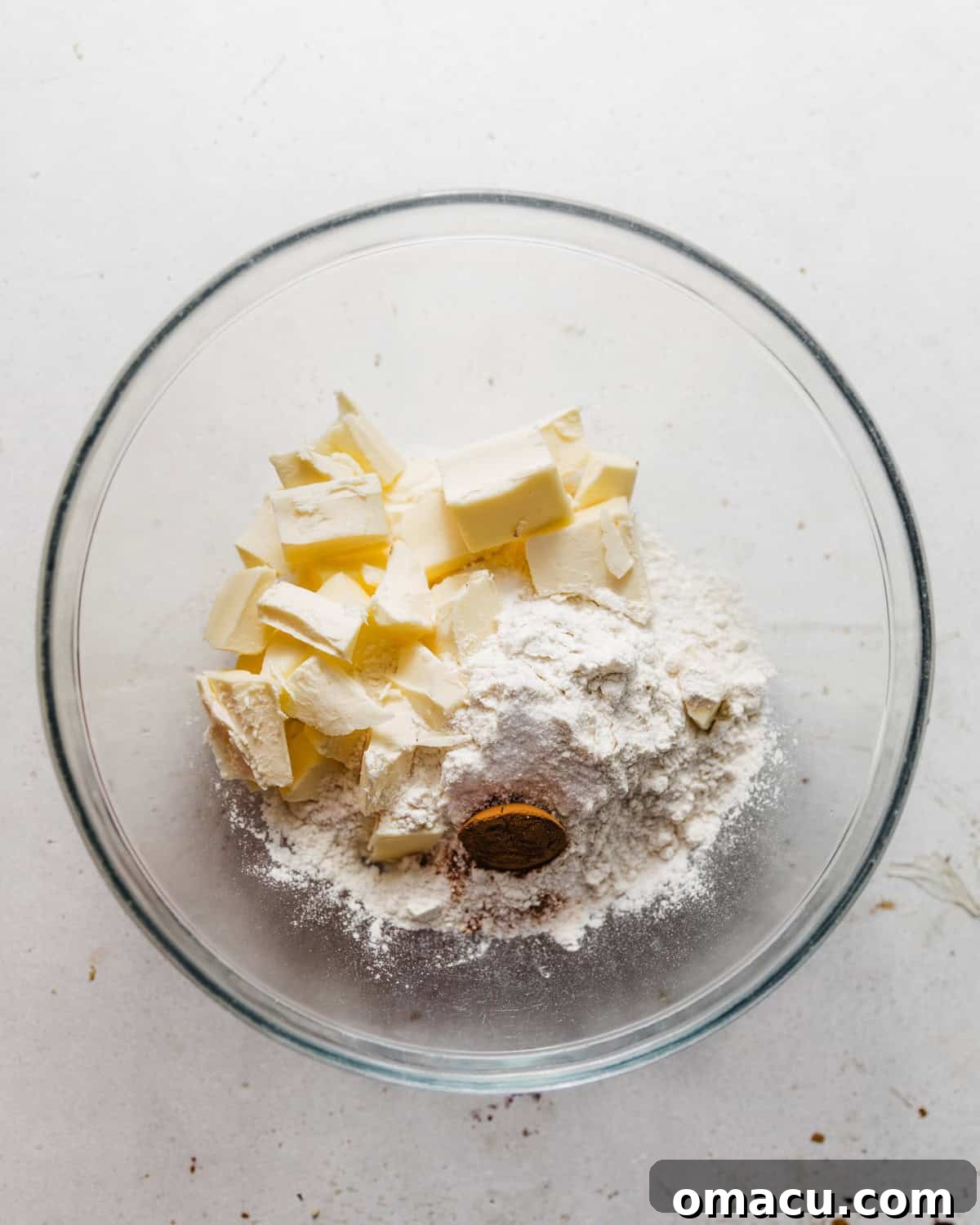 Dry ingredients for pie crust mixed together in a bowl with cold butter chunks.
