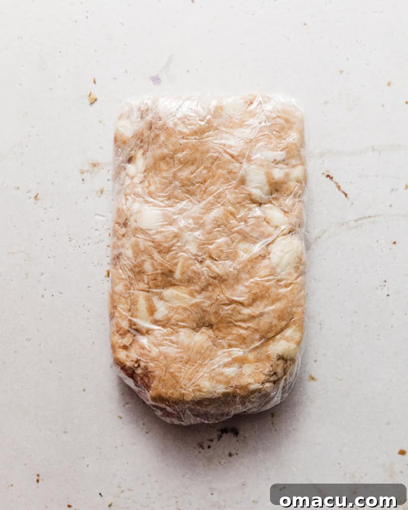 Pie crust dough wrapped tightly in plastic wrap, resting in the refrigerator.