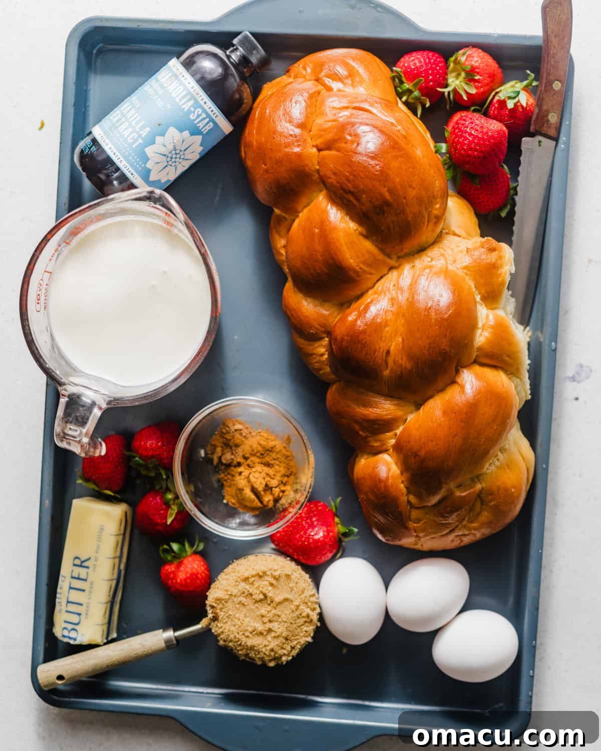 ingredients to make buttermilk french toast - challah bread, brown sugar, eggs, heavy cream, buttermilk, butter, strawberries, cinnamon, nutmeg, and vanilla extract.