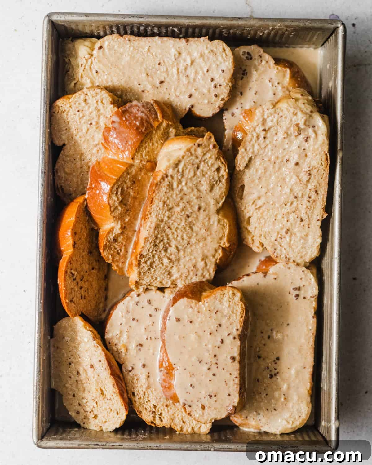sliced bread soaking in the custard in a baking dish.