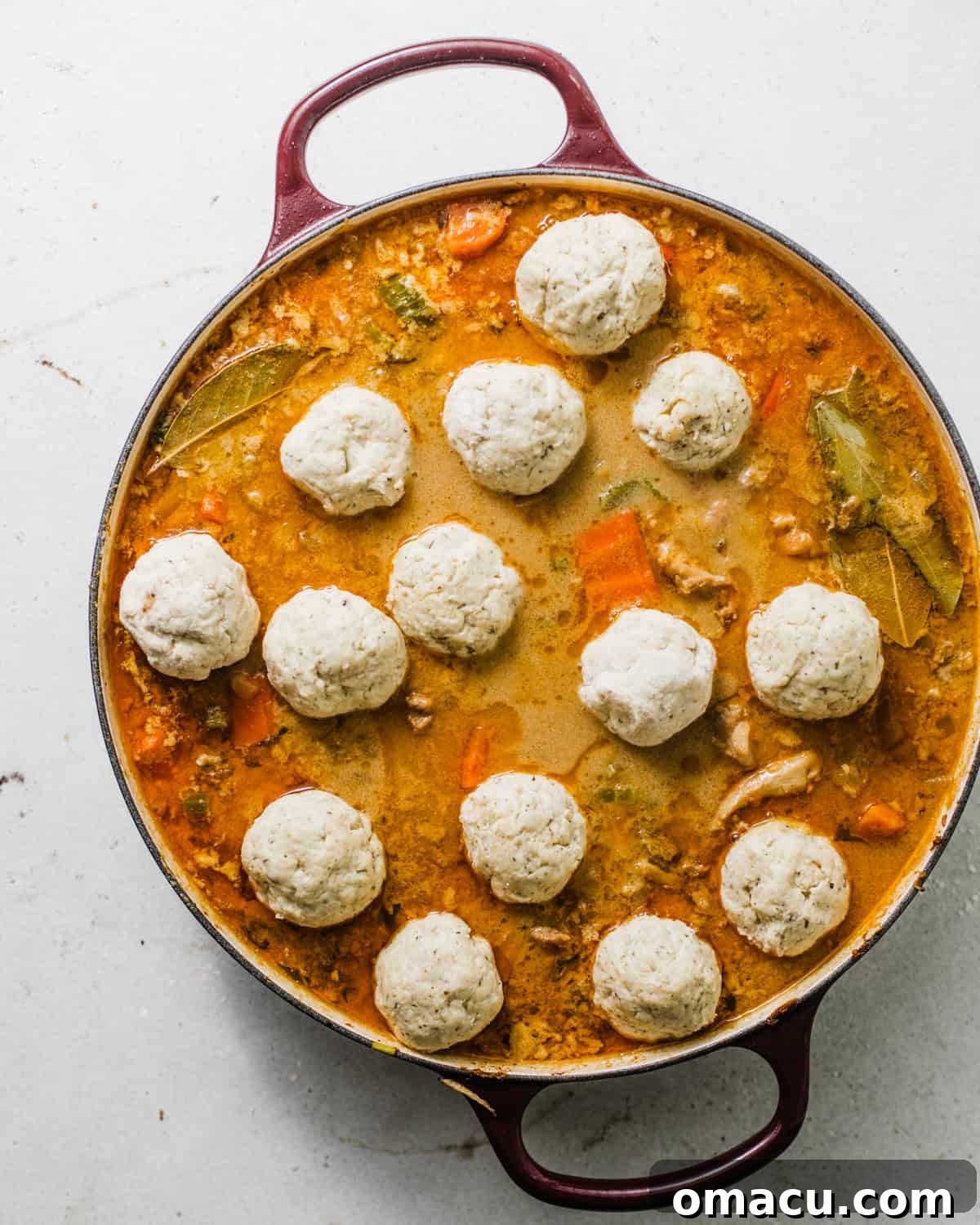 dumplings on top of chicken soup in a dutch oven.