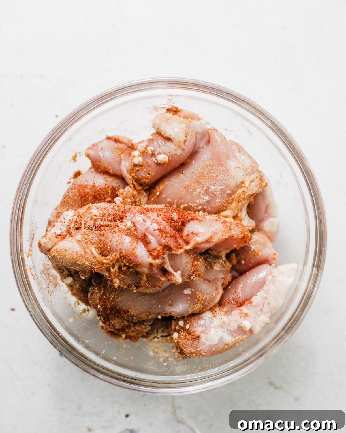 boneless skinless chicken thighs in a bowl coated with seasonings.