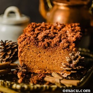 sweet potato bread with a cinnamon streusel on top on a gold tray with cinnamon sticks and pine cones.