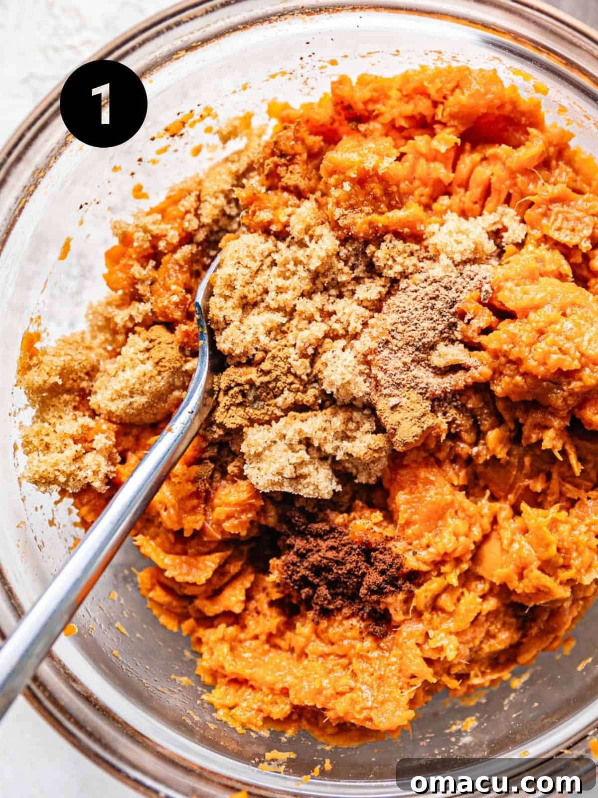 Mashed sweet potatoes in a large mixing bowl, combined with vegetable oil, brown sugar, and melted butter, forming the base of the bread batter.