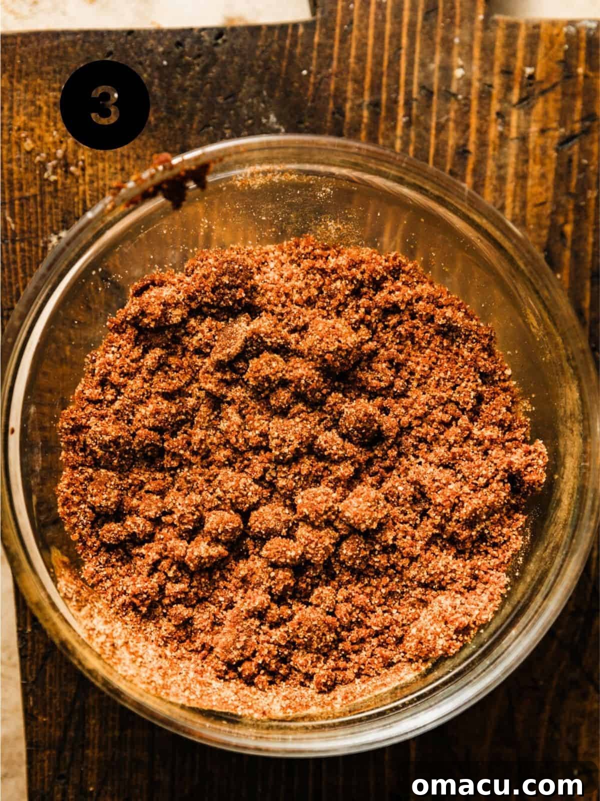 Cinnamon streusel topping, perfectly mixed to a crumbly wet sand consistency, in a small bowl, ready to be sprinkled over the bread batter.