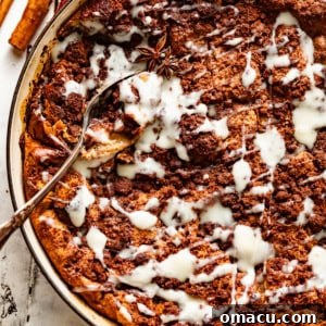 Bread pudding with vanilla sauce in a circle baking dish.