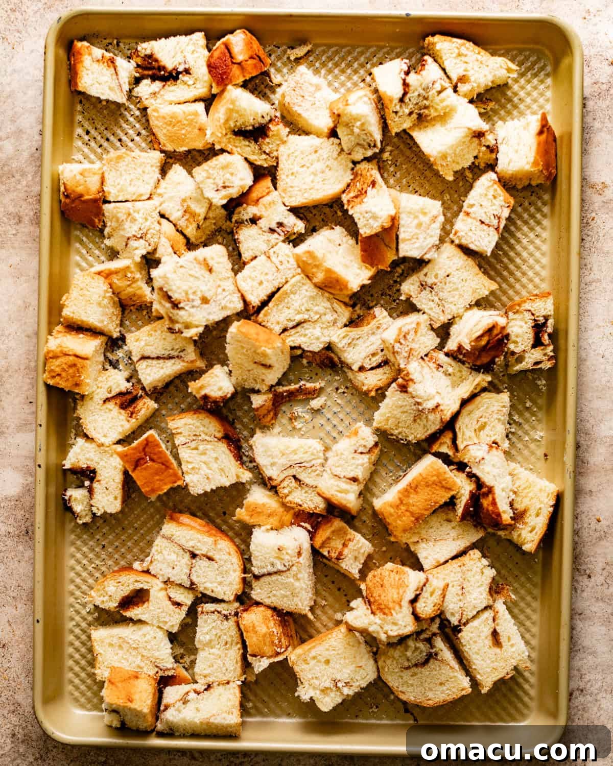 Brioche bread cut into bite-sized chunks on a baking sheet, ready for the custard.