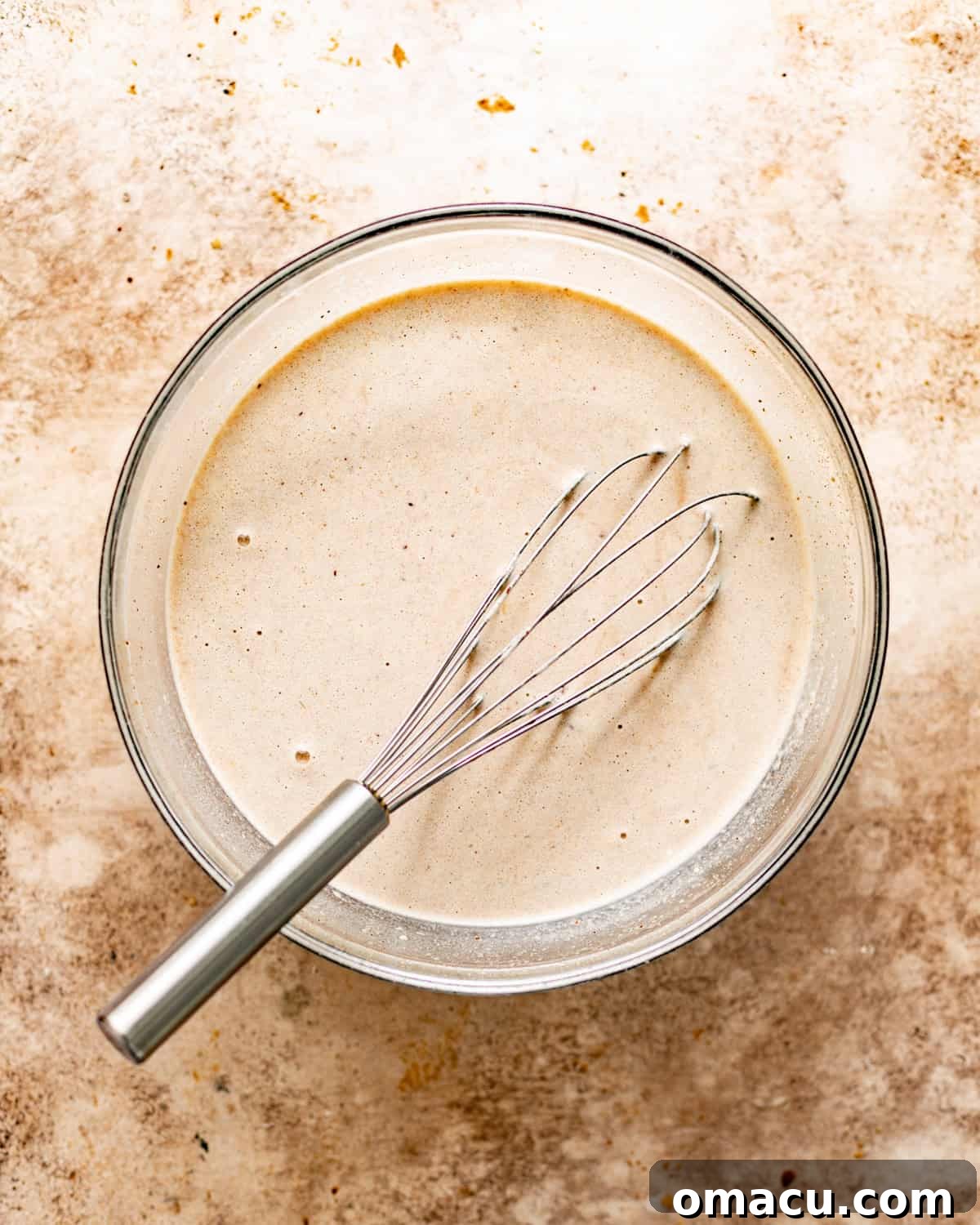 Bread pudding custard mixture whisked together in a large mixing bowl.