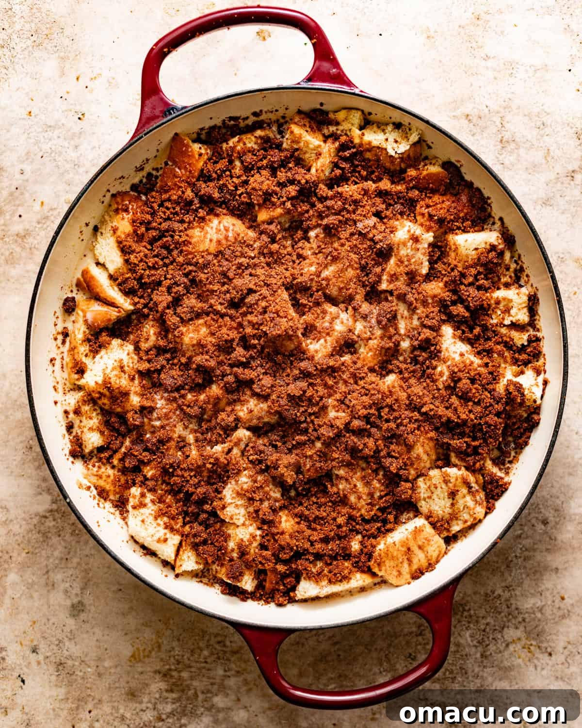 Bread pudding assembled in a 12-inch skillet with cinnamon streusel sprinkled on top, ready for baking.