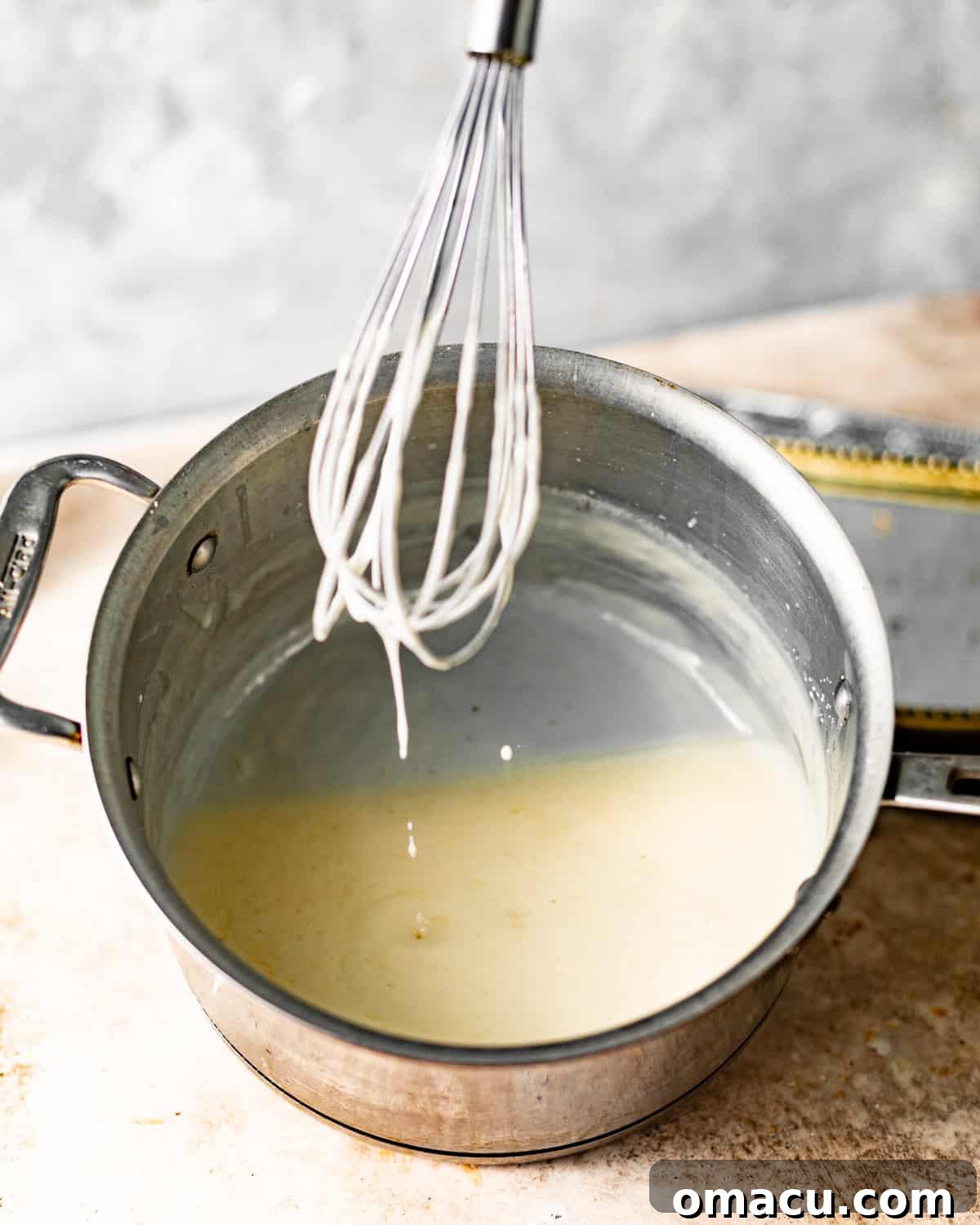 Vanilla sauce simmering gently in a small saucepan on the stovetop.