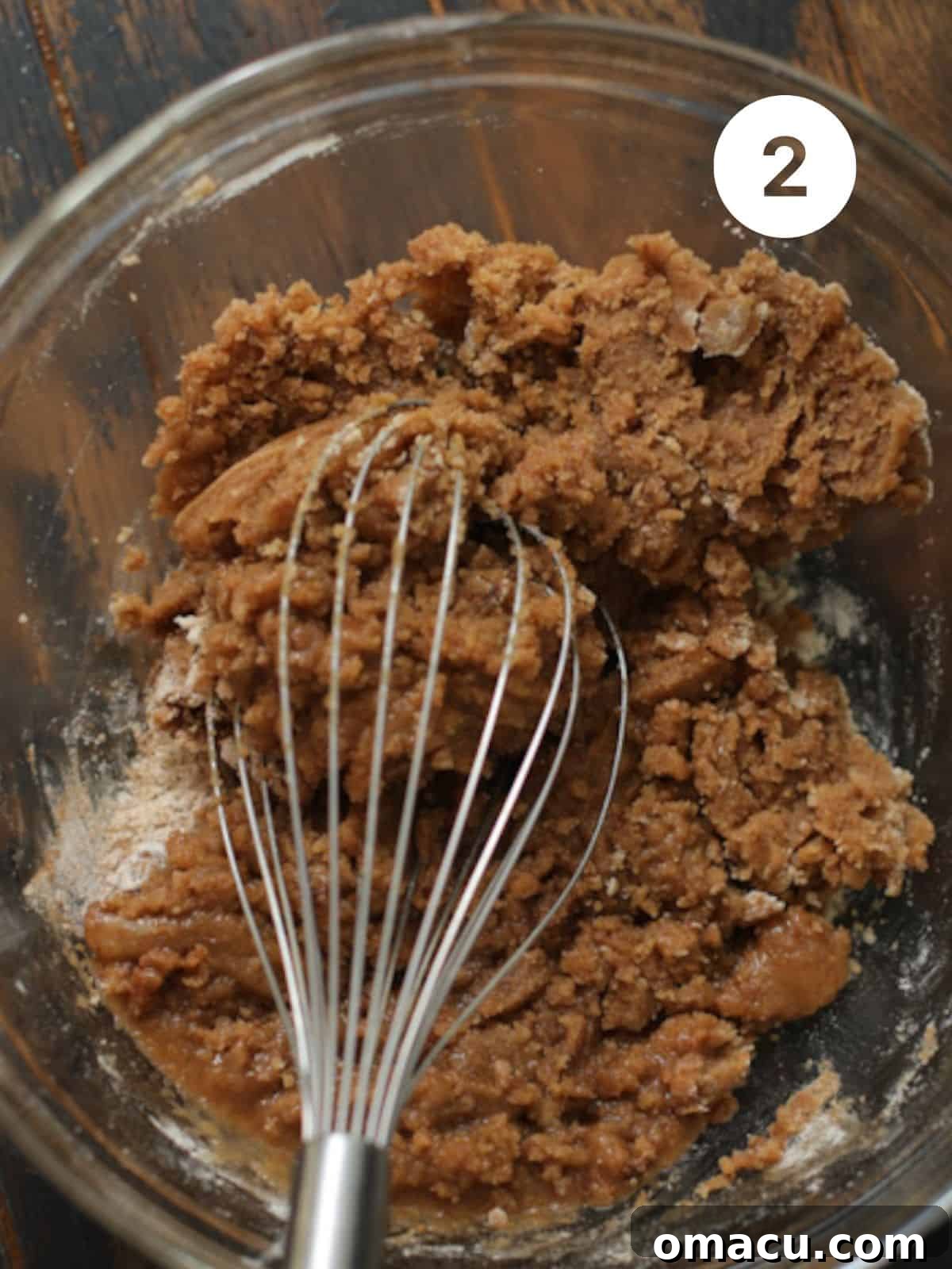 Dry ingredients and oil combined in a mixing bowl, forming a thick paste.