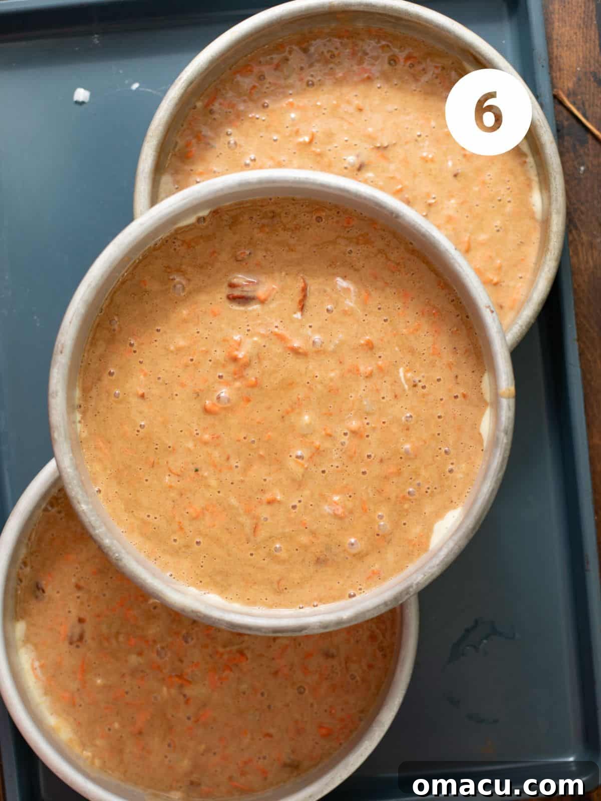 Carrot cake batter divided into three 8-inch round baking pans, ready for the oven.