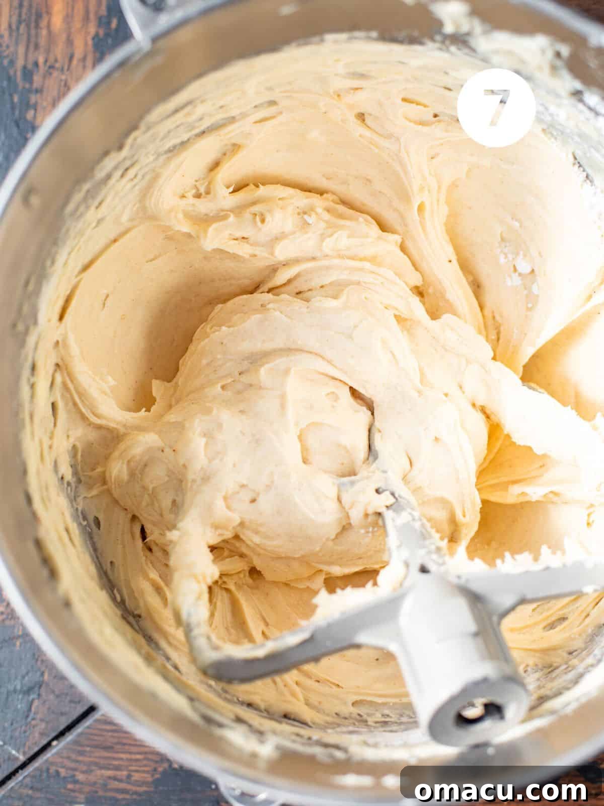 White chocolate cream cheese frosting being beaten in a stand mixer with a paddle attachment.