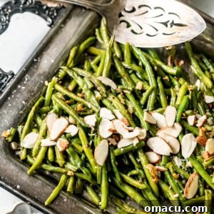 Frozen roasted green beans on a serving tray topped with garlic and almonds.