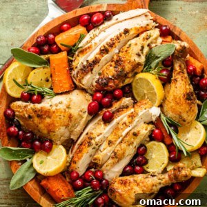 roasted chicken cut into pieces on a fancy serving tray with cranberries, herbs, and vegetables.