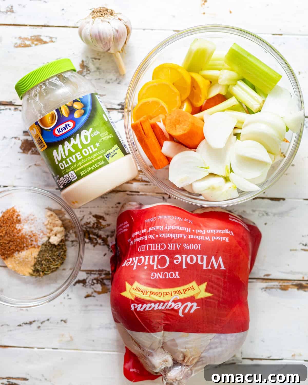 ingredients to make roasted thanksgiving chicken - whole chicken, vegetables, mayo, seasonings, and butter.