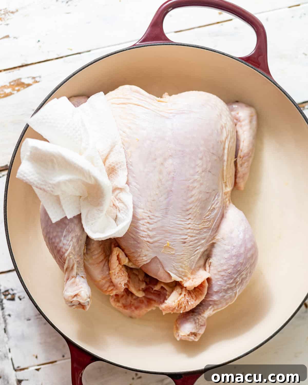a whole chicken in a roasting pan with a paper towel to pat the chicken dry. 