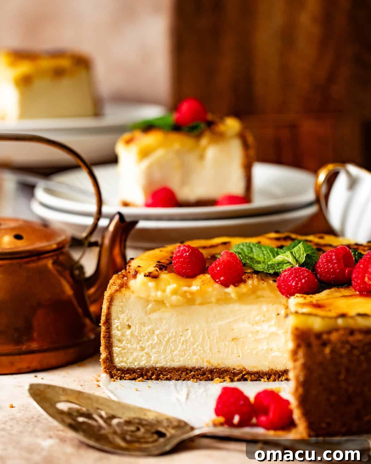 creme brulee cheesecake on a plate with fresh raspberries and a cake knife.