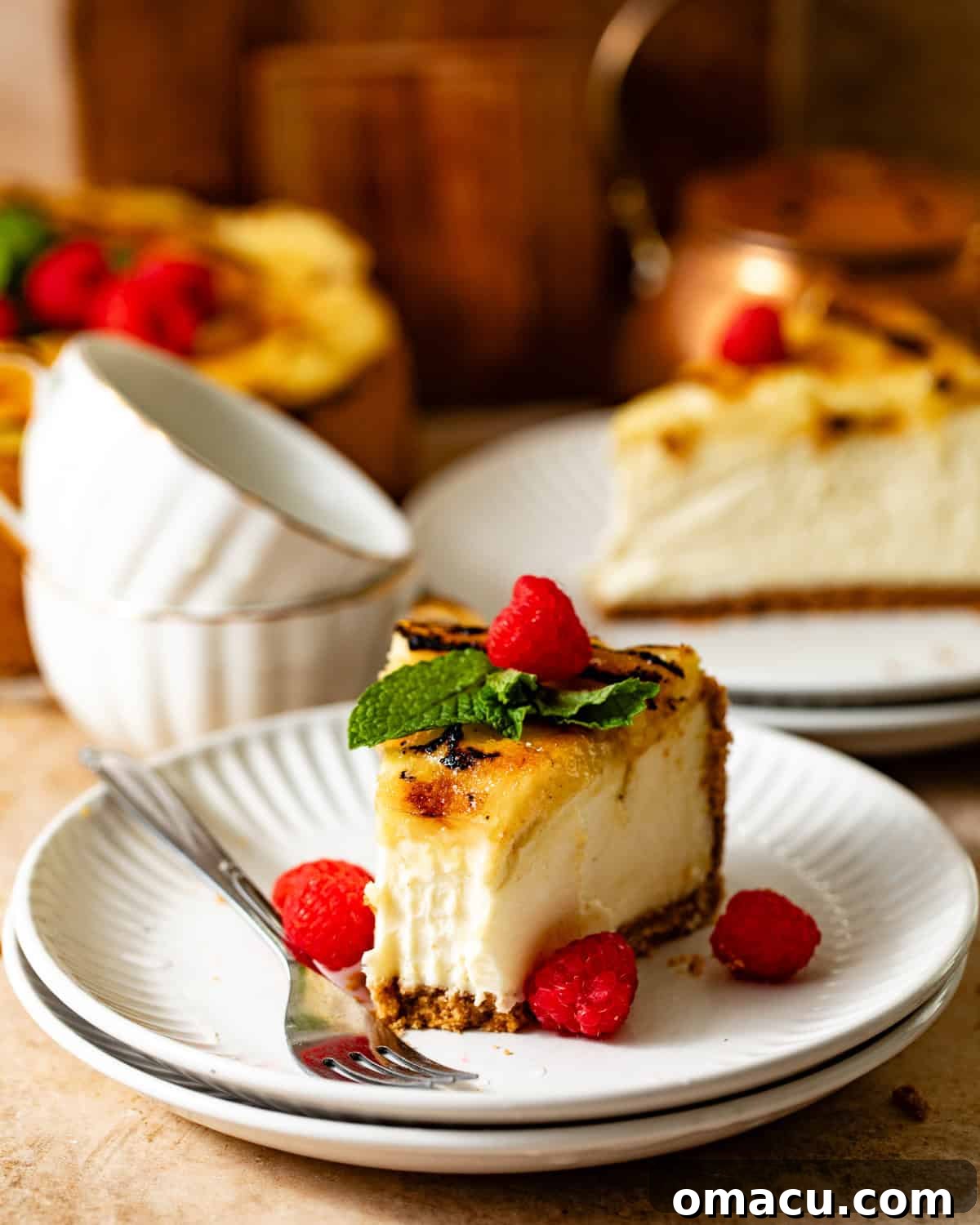 a slice of creme brulee cheesecake on a plate topped with raspberries and mint.