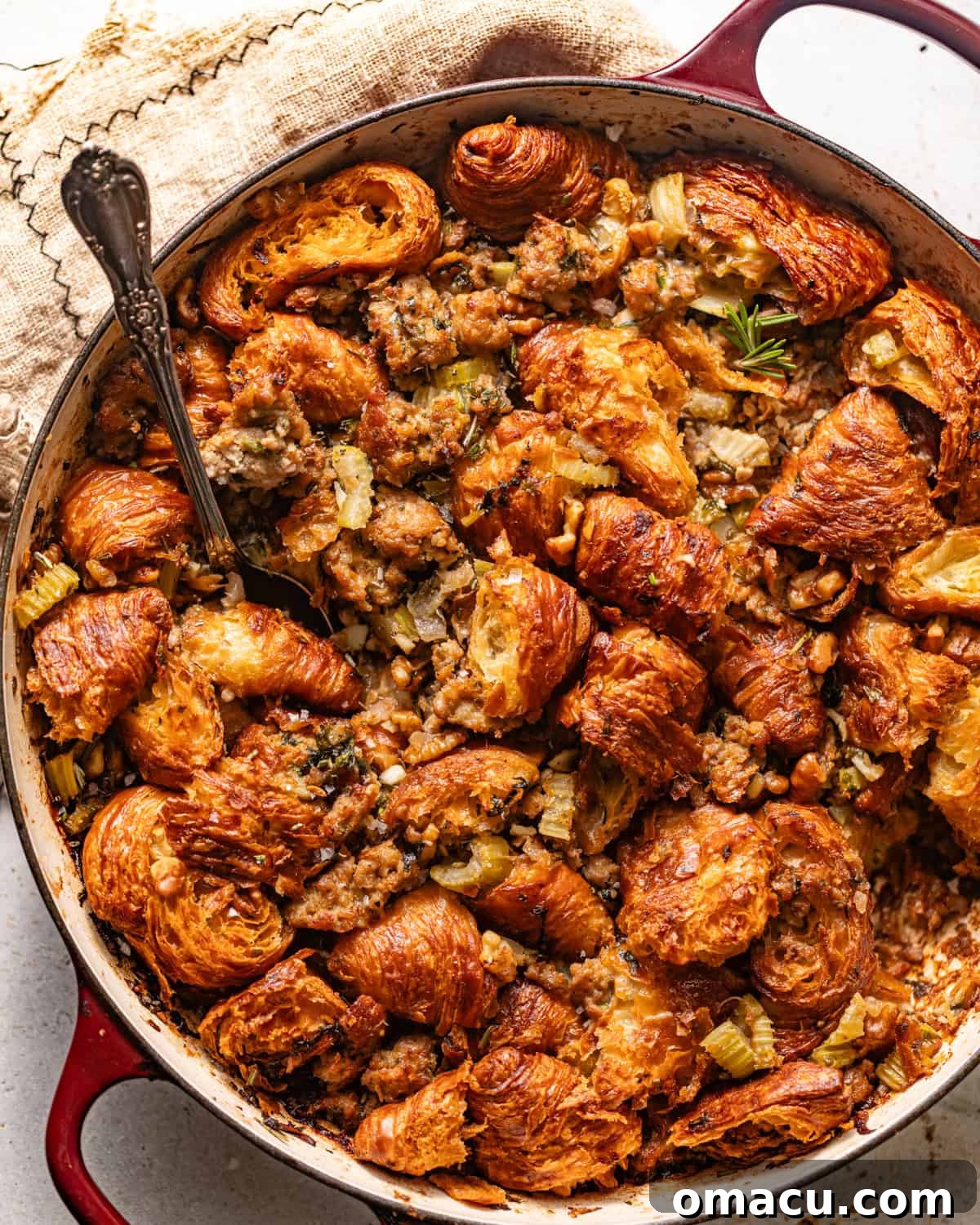 A large pan of golden-brown croissant stuffing, beautifully assembled and ready for baking, showcasing its rich texture and festive ingredients.