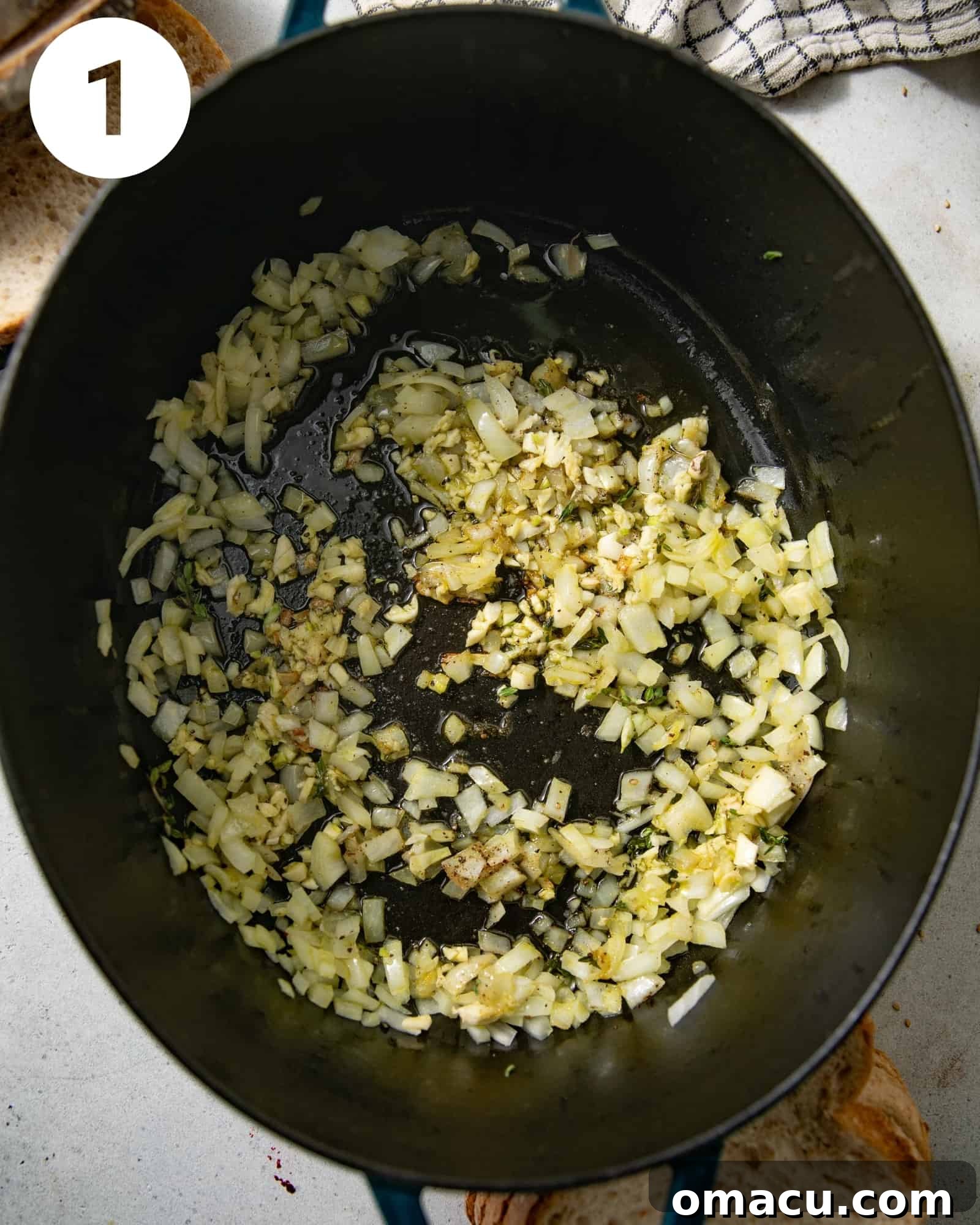 Sautéed onions, garlic, olive oil, and thyme cooking in a large Dutch oven.