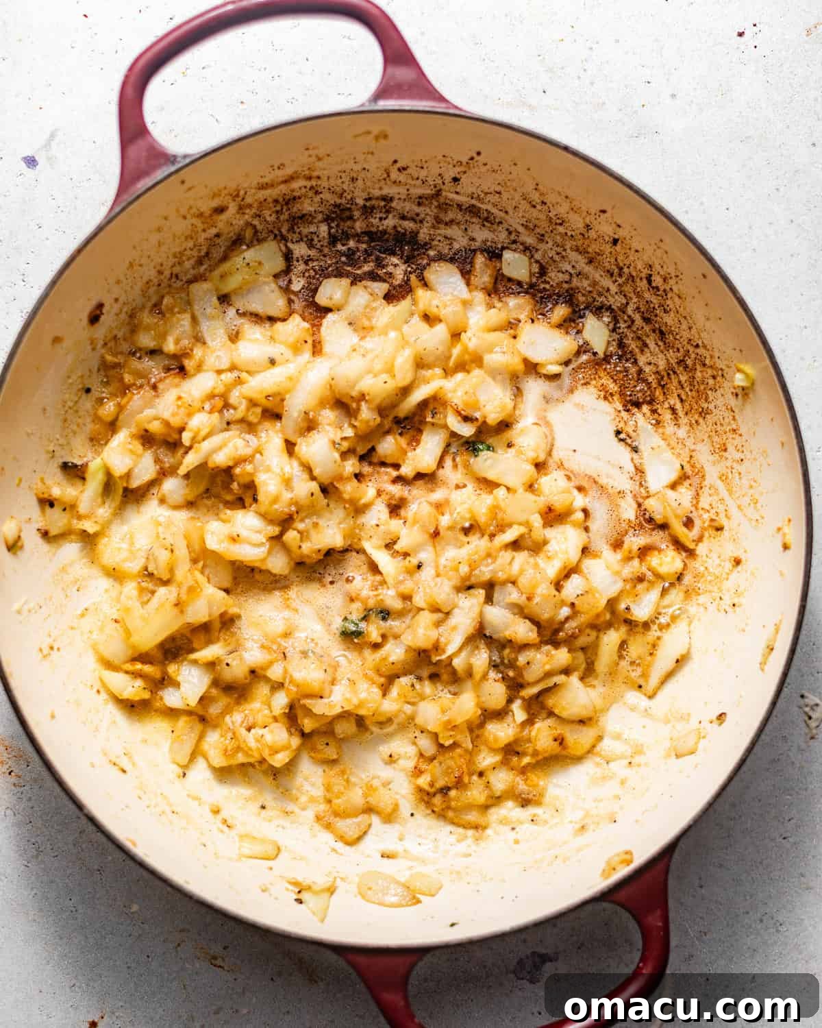 Sautéed onions and minced garlic with seasonings in a large skillet, forming the base of the roux.