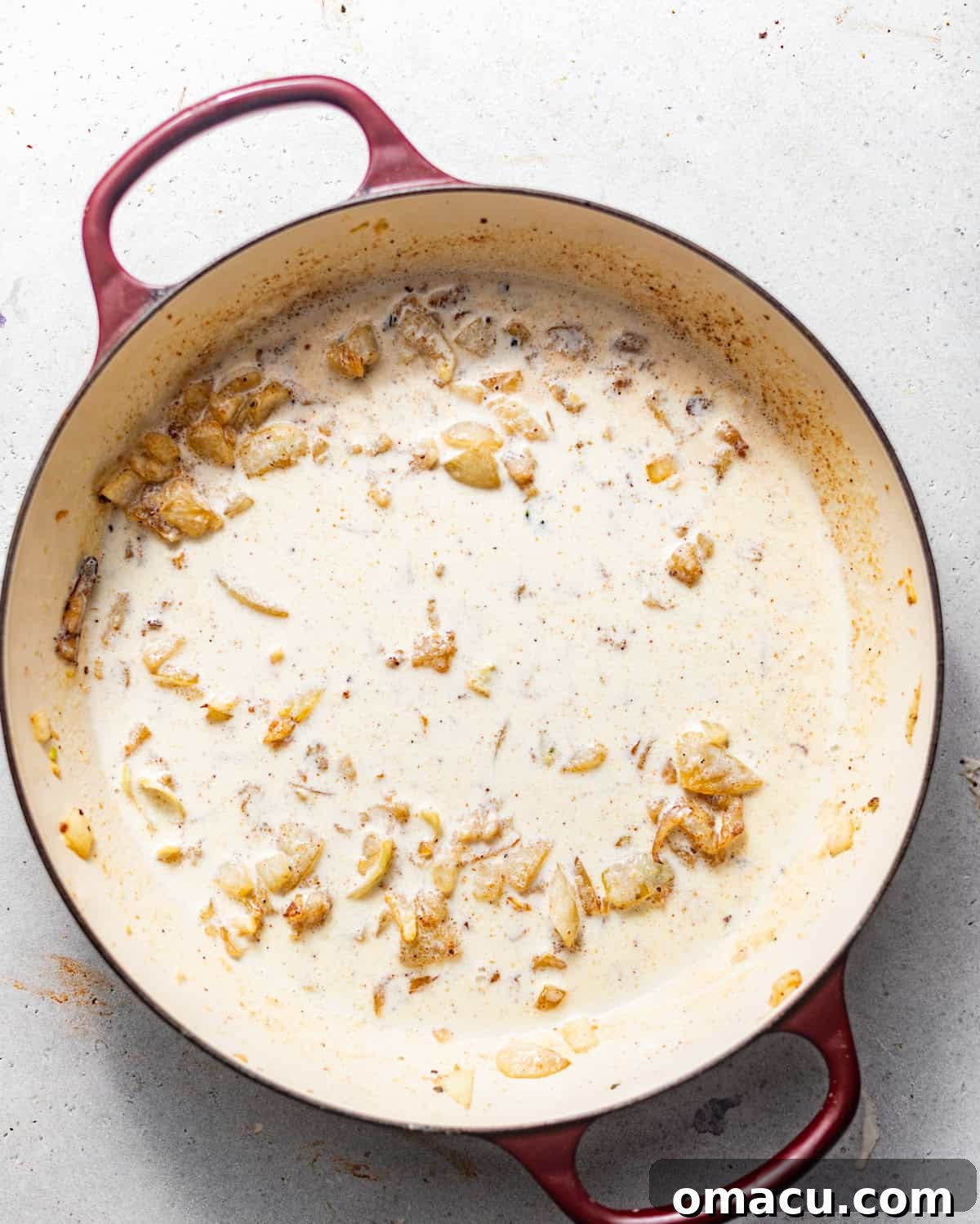 A rich, creamy béchamel sauce simmering in a sauté pan, thickened to perfection.