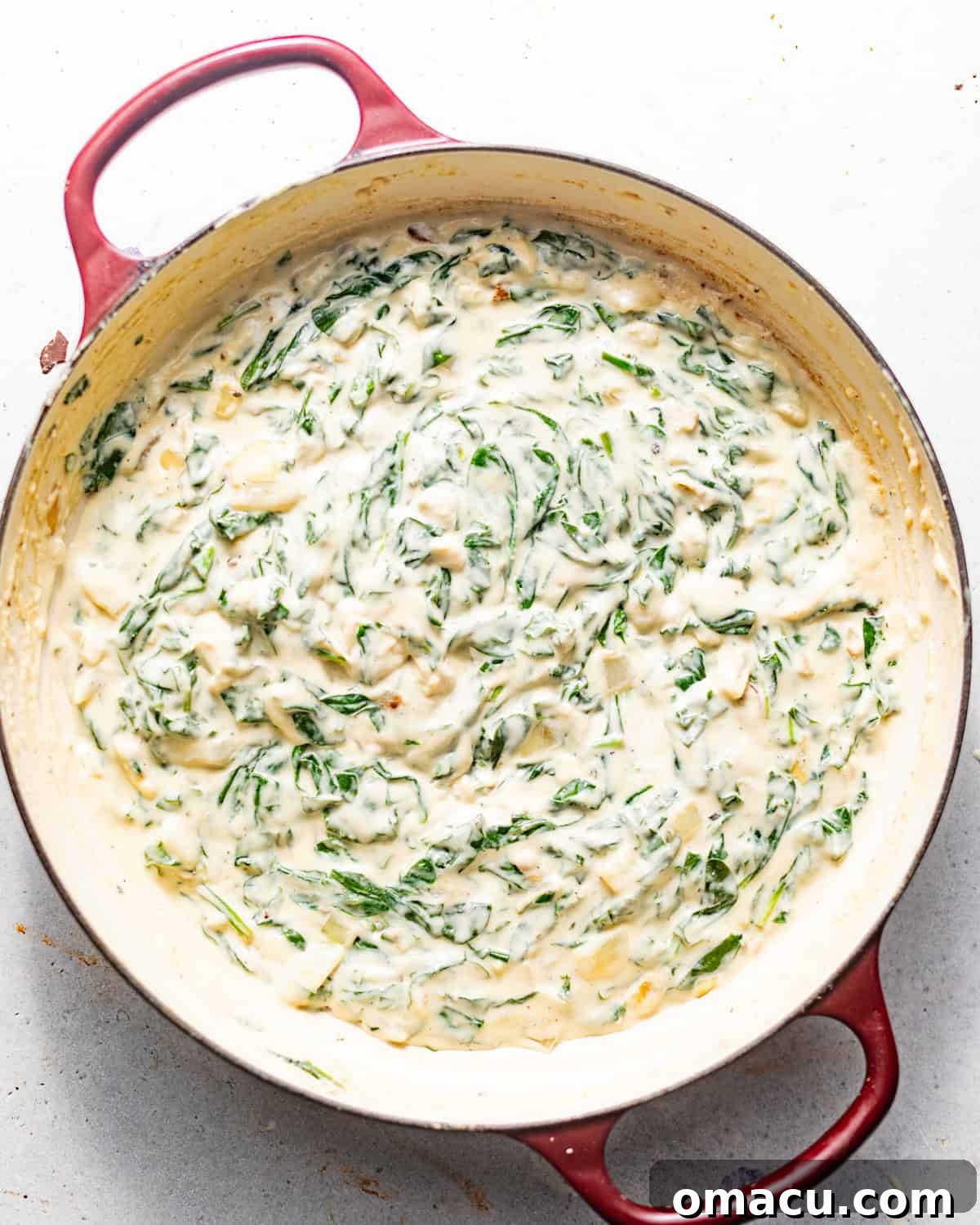 Chopped spinach and Parmesan cheese folded into the creamy sauce, creating the final mixture.