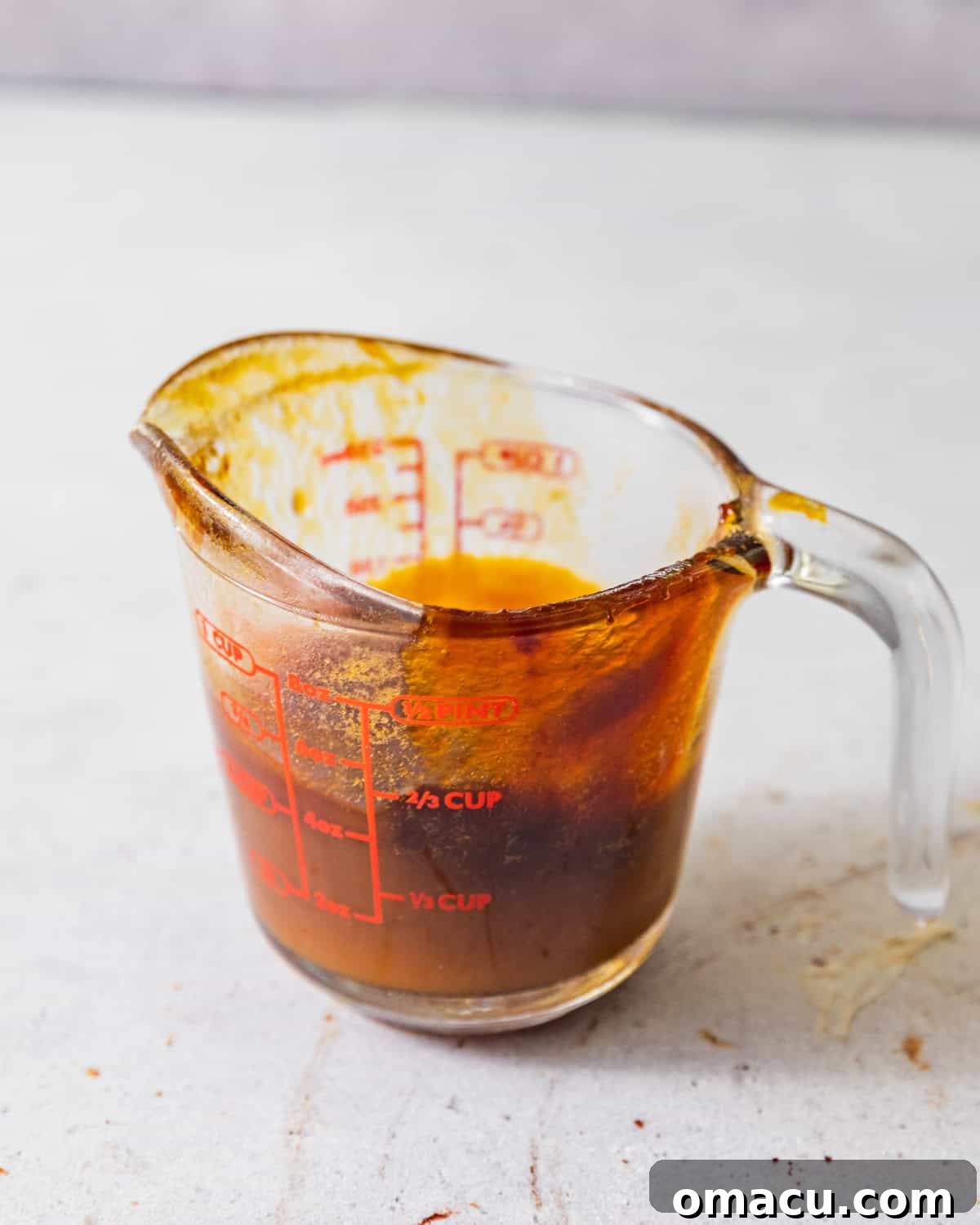 Pineapple juice being boiled down in a saucepan to create a thick concentrate, then cooling in a glass measuring cup.