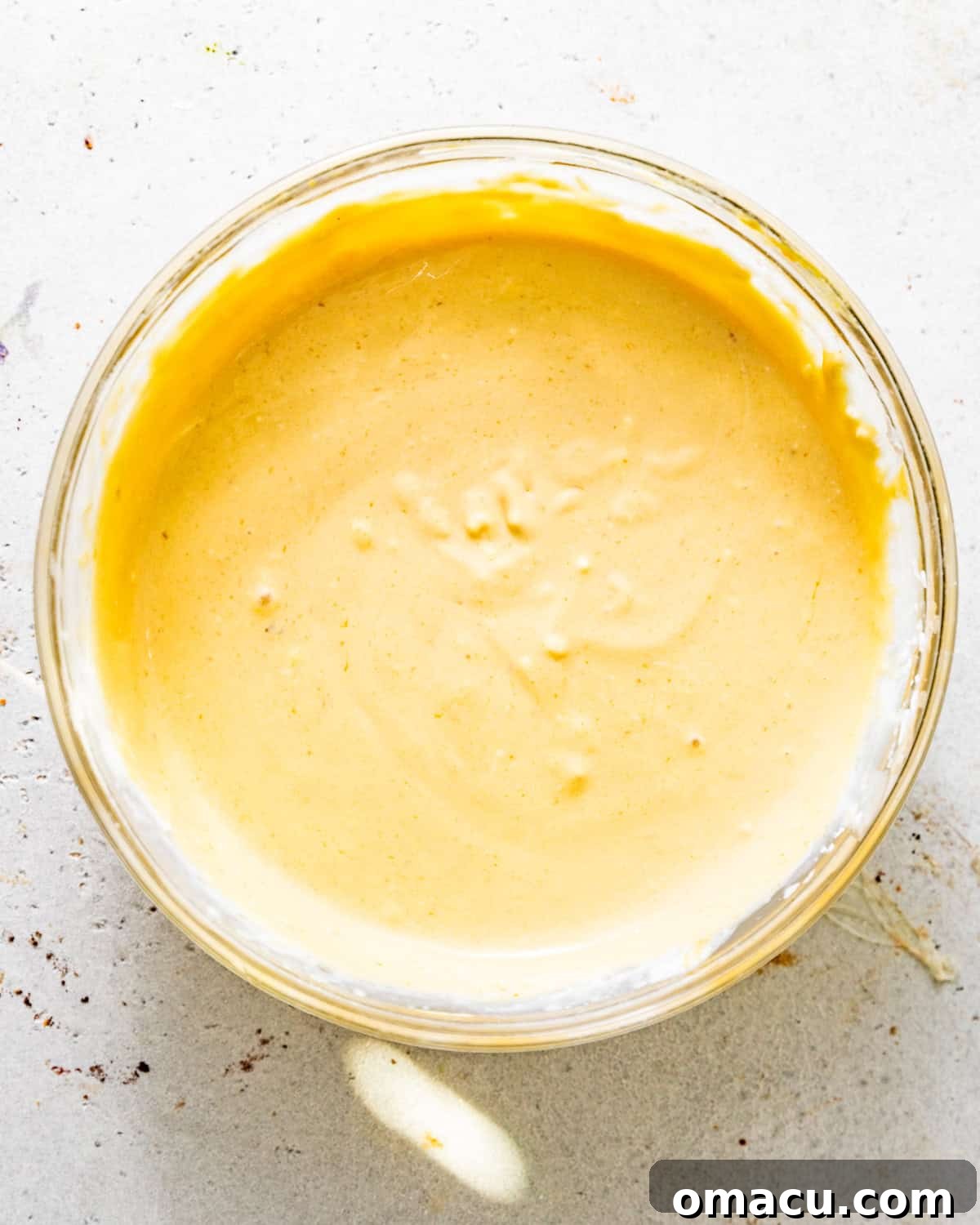A small bowl containing the mixed pineapple juice concentrate, crushed pineapples, sour cream, heavy cream, kosher salt, and cornstarch, ready to be added to the main batter.