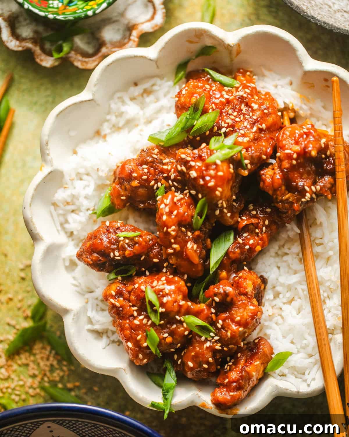 Crispy orange chicken and rice served in a bowl with chopsticks, ready to eat.