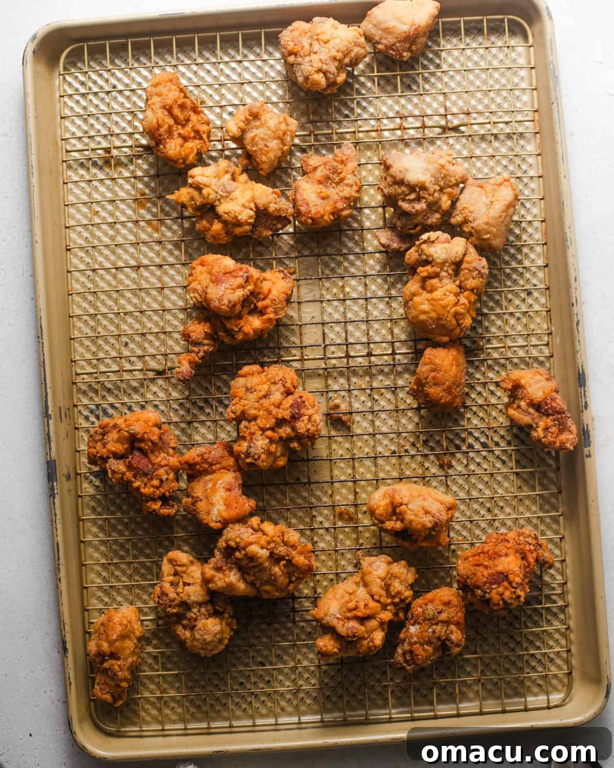 Double-fried chicken bites resting on a wire rack to drain excess oil.