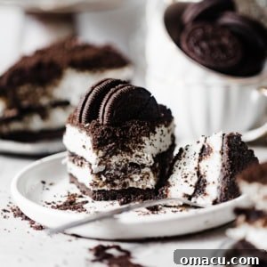 sliced oreo cheesecake on a plate topped with crushed oreo cookies.