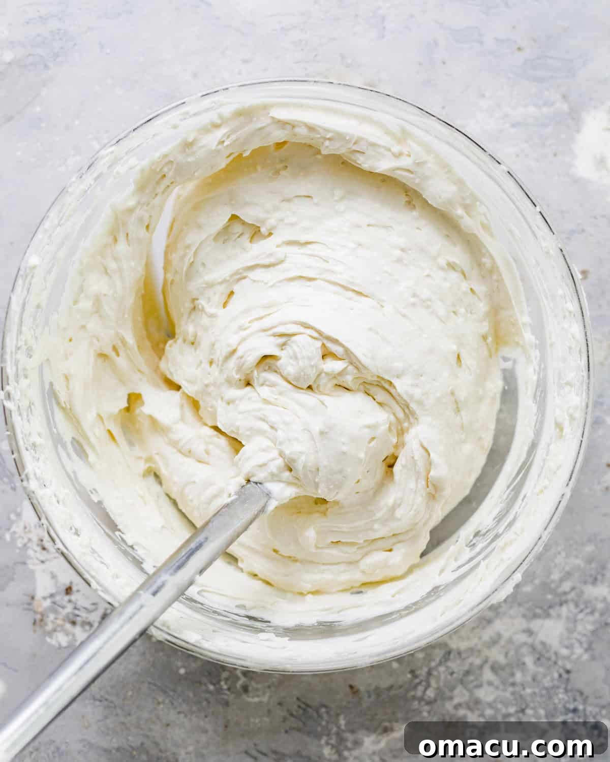 A large mixing bowl containing the creamy cheesecake filling ingredients, perfectly blended to a smooth consistency with a hand mixer resting nearby.