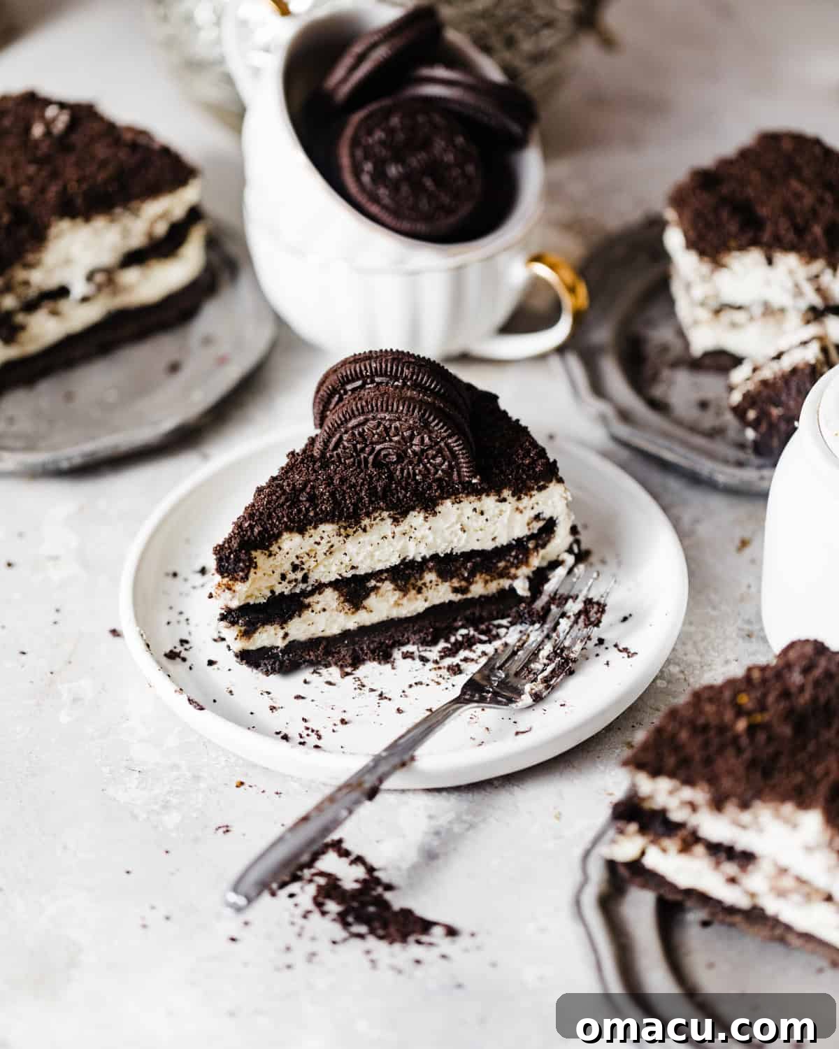 Two individual slices of no-bake Oreo cheesecake, each on a small white plate with a fork, emphasizing the layered texture and inviting presentation.