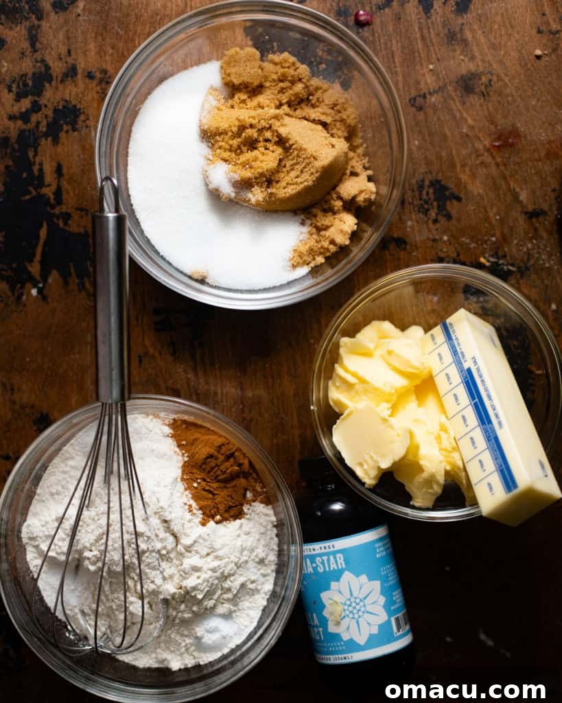 Arrangement of ingredients for snickerdoodle cookie bars: sugar, brown sugar, butter, flour, baking powder, cream of tartar, vanilla extract, cinnamon, and kosher salt.