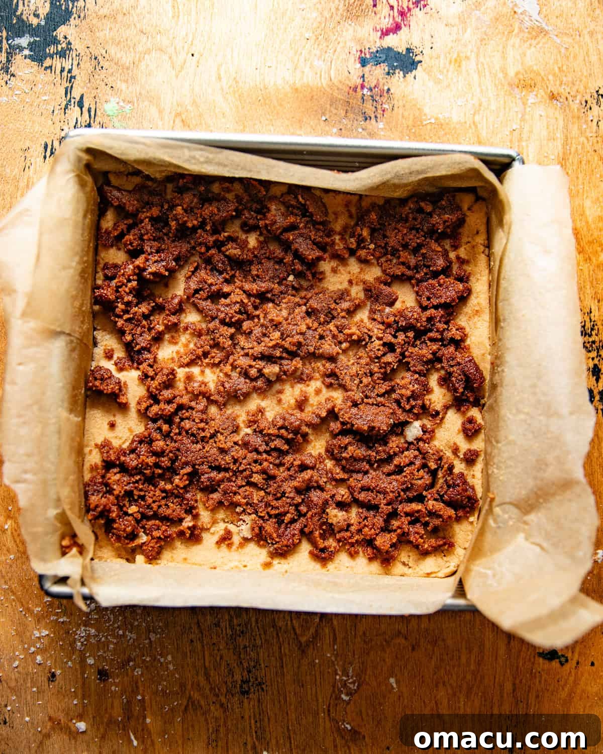 Baked snickerdoodle cookie bars in a parchment-lined baking dish, golden brown and perfectly set.