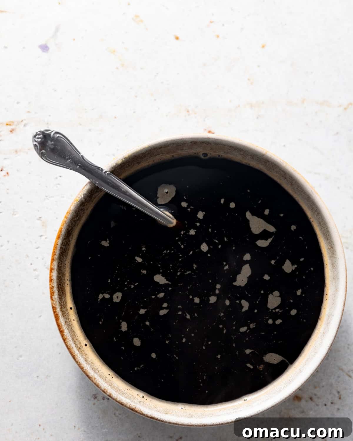 A medium bowl filled with the rich, dark espresso coffee soak, ready for dipping ladyfingers to infuse them with bold coffee flavor for tiramisu.